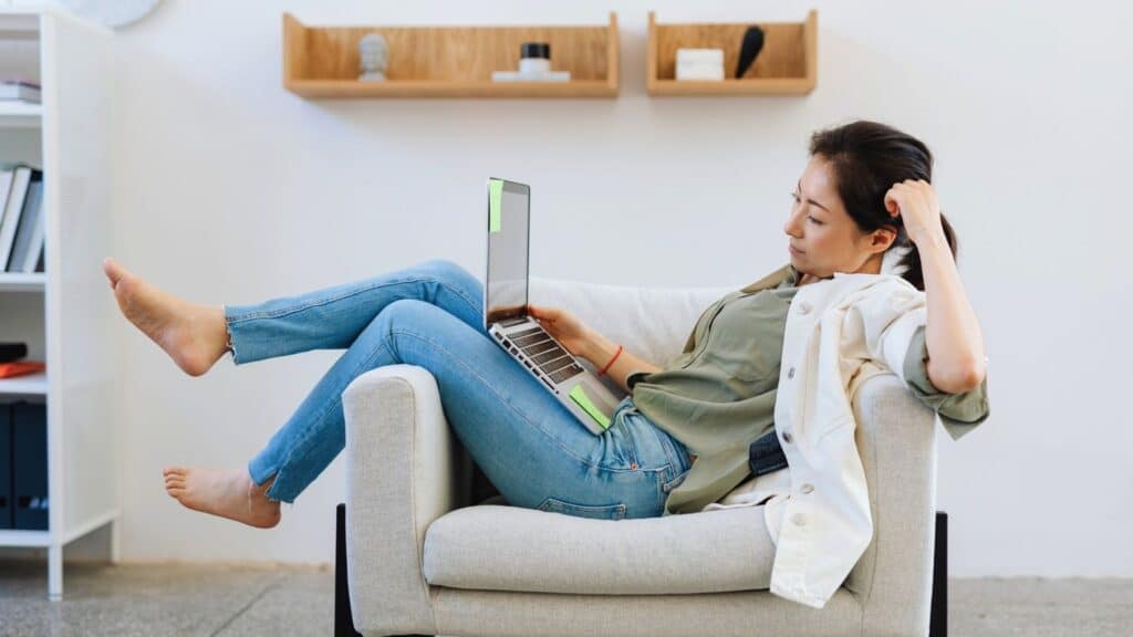 woman relaxing comfortable on a seat in living room playing on laptop