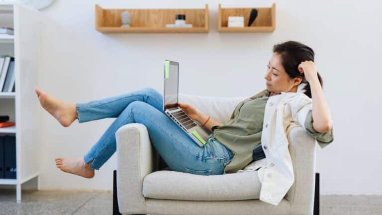 save on heating woman relaxing comfortable on a seat in living room playing on laptop