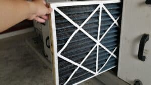 person pulling out an old HVAC filter out of machine